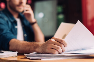 selective focus of businessman touching documents on desk