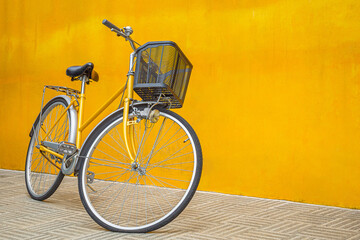 A yellow retro bicycle parking against yellow wall - Powered by Adobe