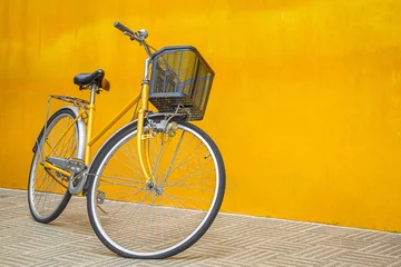 Fotobehang A yellow retro bicycle parking against yellow wall © meeboonstudio