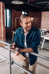 selective focus of cheerful businessman holding smartphone and folder in office