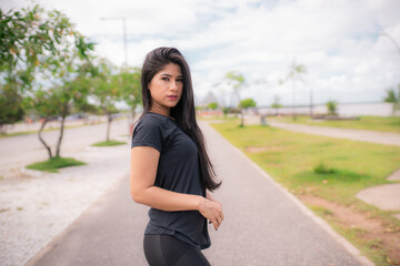 Mulher jovem e bonita tocando as mãos depois da corrida olhando para a câmera.