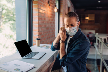 businessman wearing medical mask near laptop with blank screen