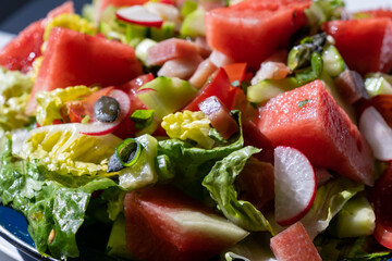 close up view of a healthy vegetable and watermelon salad with bits of bacon