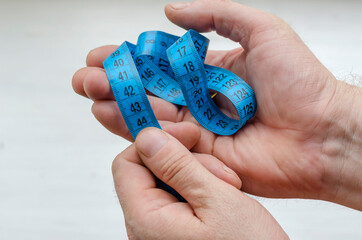 Male hands holds the blue measuring tape. Emphasis on the number 40, 41, 42, 44.