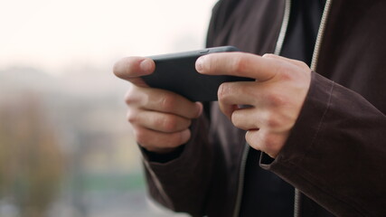 Male hands holding mobile phone outdoors. Guy hands using mobile phone outside.