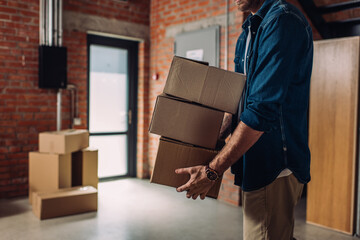 cropped view of businessman holding boxes and moving in new office
