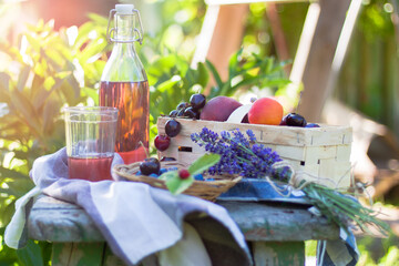 picnic in the garden with glass bottle of lemonade and fresh summer fruits
