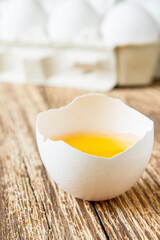 Close-up of fresh egg yolk on the background of eggs in paper tray on wooden surface