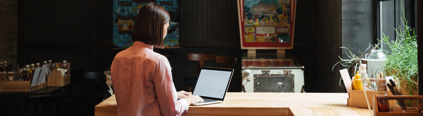 Back view of brunette woman sitting by the table