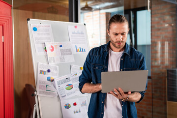 bearded businessman using laptop near charts and graphs