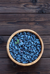 Honeysuckle in a wooden dish with copy space for text. Fresh harvest of honeysuckle berries from the garden. Top view.