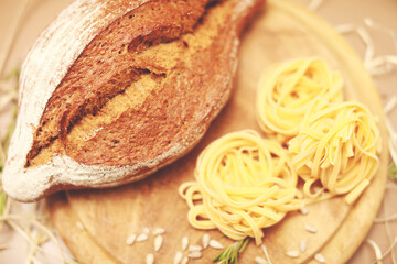 view from the top on fresh homemade bread with fettuccine and rosemary on wooden cutting board 