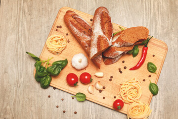 close up view on bread with red pepper,garlic,basil,spaghetti,sunflower oil and rosemary on wooden...