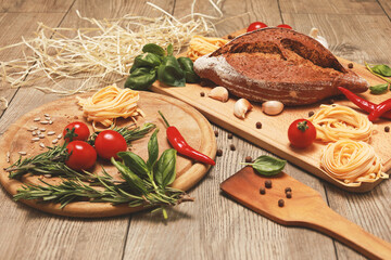 close up view on bread with red pepper,garlic,basil,spaghetti,sunflower oil and rosemary on wooden...
