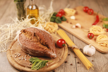 close up view on bread with red pepper,garlic,basil,spaghetti,sunflower oil and rosemary on wooden board.