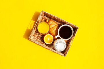 Wicker basket with a cup of coffee, croissant, milk and orange juice. Breakfast
