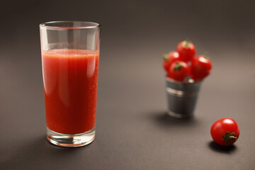 Close up view of tomato juice in glass and around cherry tomatoes isolated on black background with copy space 