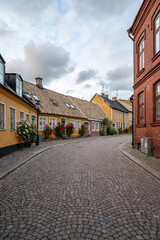 A cobblestoned street bordered with yellow and red townhouses in the historic old town of Lund, Sweden