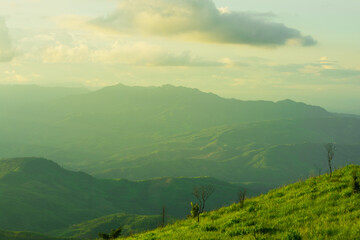 Sunset and mountains interspersed with green grass