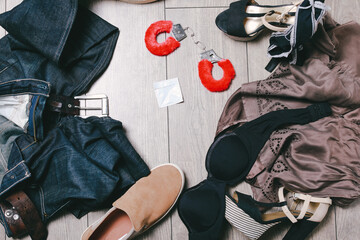 Scattered clothes man and woman with condom and sex toy red handcuffs on the floor after party before foreplay of sex