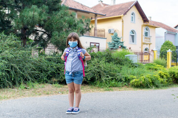 Fototapeta na wymiar Girl goes to school with a mask on her face