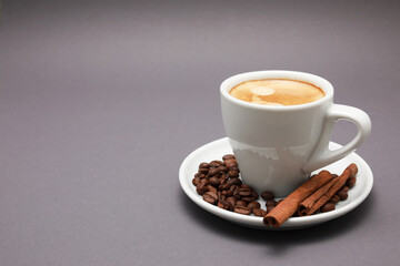 White cup of coffee, around beans, note book and pen isolated color background.