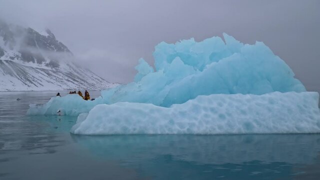 tourist's zodiak boat sailing near a beautiful scalptured ice block