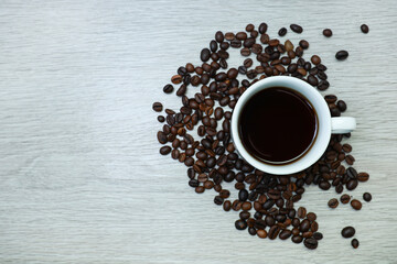 View from above of cup of coffee and coffee beans on wooden table 