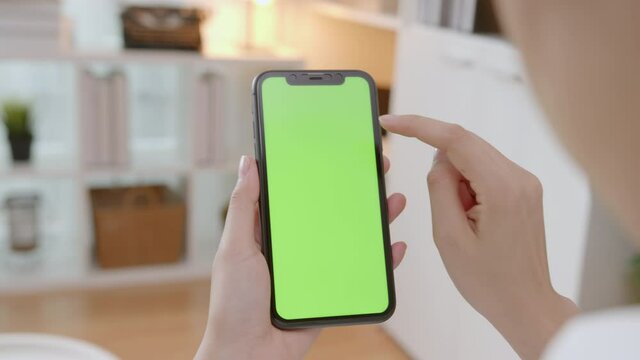 handle shot of woman holding mockup smartphone green screen on the sofa at home.