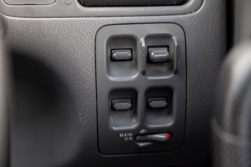 Buttons for controlling windows with opening and closing and electric drives and locks for black doors with plastic upholstery in a modern car located on the central panel near the steering wheel.