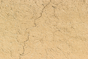 Adobe - clay and straw material weathered wall of rural old country house close-up as clay background.