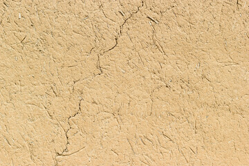 Adobe - clay and straw material weathered wall of rural old country house close-up as clay background.