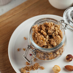  Homemade granola with nuts in a glass jar close-up. Fast and healthy breakfast concept, vegetarian breakfast.