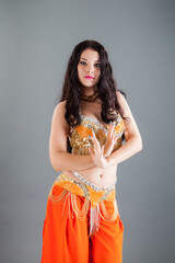 closeup portrait of young woman with long dark hair in orange belly dancer costume
