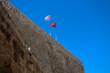 Two flags on the stone wall of the fortress of Kyrenia. Kyrenia. Cyprus.