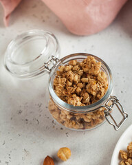  homemade granola with nuts in a glass jar close-up. Fast and healthy breakfast concept, vegetarian breakfast.