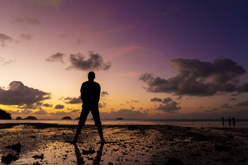 Fototapeta na wymiar Silhouette of a man on the beach at sunset. Man rejoices meets the sunset