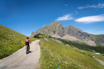 active senior woman riding her electric mountain bike below the seven summits of Churfirsten in...