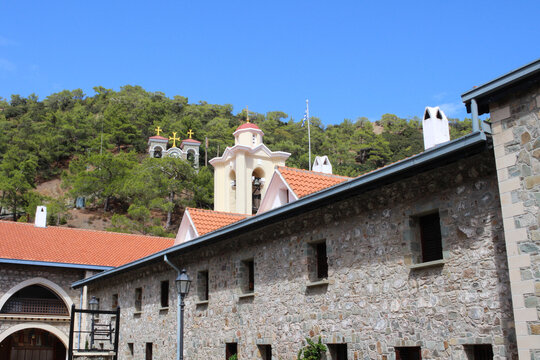 View from the courtyard of the building of the Kikk monastery and the bell tower, against the background of the forest and blue sky. Cyprus.