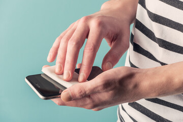A man wipes a mobile phone with a damp wipe