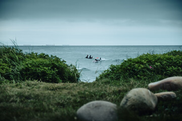 Surfers silhouette in the water at foggy summer day with sea background