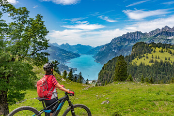 active senior woman riding her electric mountain bike below the seven summits of Churfirsten,...