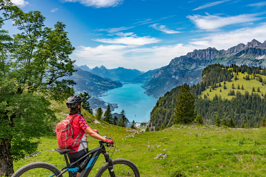 active senior woman riding her electric mountain bike below the seven summits of Churfirsten, enjoying the awesome view down to Lake Walensee Canton St. Gallen, Switzerland