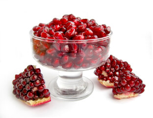 Pomegranate with seeds in a glass bowl isolated on a white background.