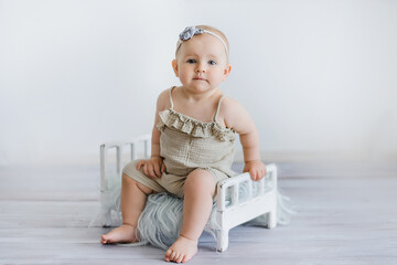funny baby on bed in children room. Greeting card. Congratulations on Mother's Day. Cute baby girl 9 months sitting and crawling. Sitter session