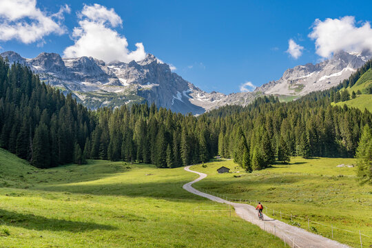 senior woman riding her electric mountain bike up to the Lindau Hut below the famous summits of Drusenfluh and Three towers in the Montafon Area of Vorarlberg Austria