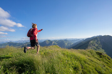 Fototapeta na wymiar active senior woman mountain running in the early evening in warm dawn light on the ridge of the Nagelfluh chain in the Allgau Alps near Immenstadt, Bavaria, Germany