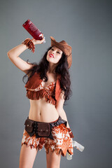 pretty brunette girl in frank cowboy costume and hat poses with bottles in hands
