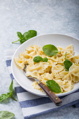 Curly bow-shaped paste with basil on concrete table