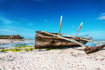 Old wooden boat on white sand near ocean in Zanzibar